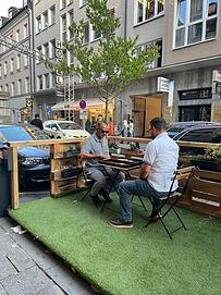 Hier haben sich zwei Anwohner zum Backgammon-Spielen in eins der Parklets gesetzt - unter das kleine Wanderbäumchen.