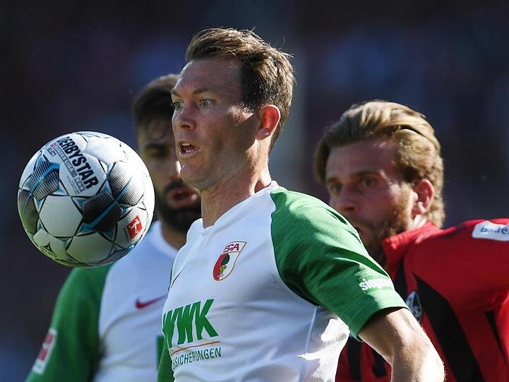 Fußball: Bundesliga, SC Freiburg - FC Augsburg, 5. Spieltag im Schwarzwaldstadion. Stephan Lichtsteiner (l) vom FC Augsburg schaut auf den Ball, Lucas Höler (r) vom SC Freiburg bleibt hinter ihm zurück. Foto: Patrick Seeger/Archiv