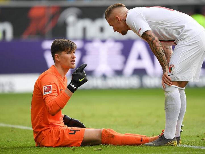 Augsburgs Torwart Gregor Kobel (l) sitzt neben Jonathan Schmid verletzt am Boden. Foto: Arne Dedert