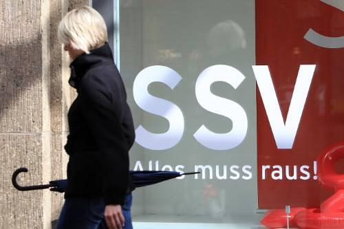 Kundin mit Schirm: Wegen des durchwachsenen Wetters sind die Lager vor dem Sommerschlussverkauf heuer noch recht voll.