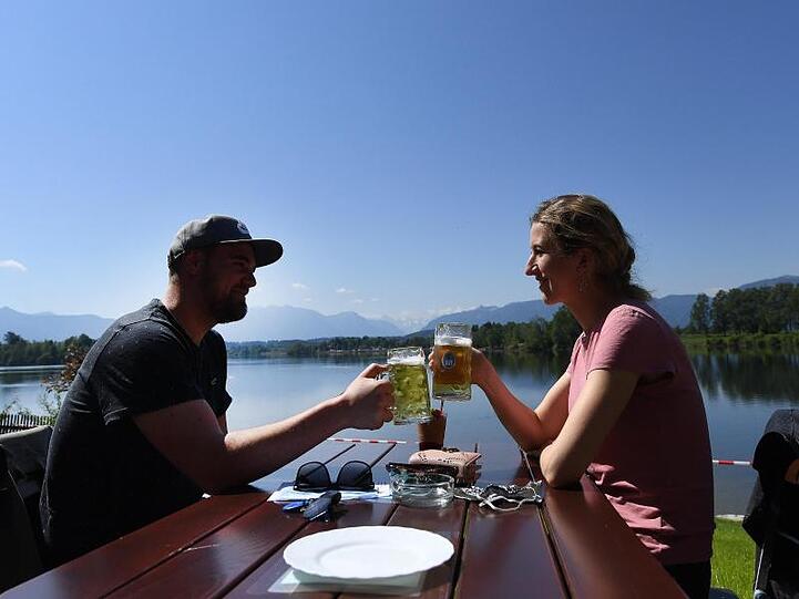 Ein Paar genießt ihr Bier in der Sonne in einem Biergarten. Foto: Angelika Warmuth/dpa