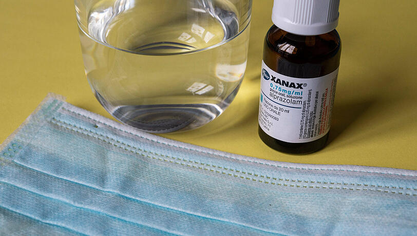 Ein Fläschchen mit Xanax steht neben einem Glas Wasser auf einem Tisch.