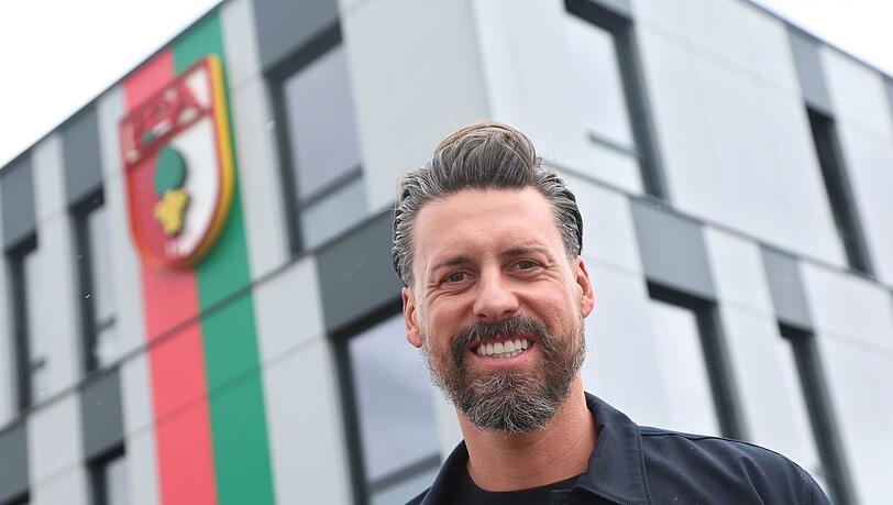 Der neue Trainer Sandro Wagner posiert vor der Geschäftsstelle des FC Augsburg.