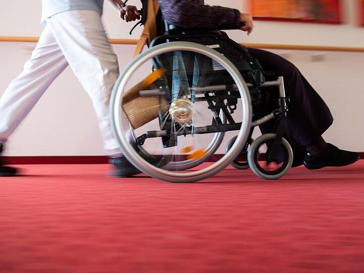 Ein Pfleger eines Pflegeheims schiebt eine Bewohnerin mit einem Rollstuhl. Foto: Tom Weller/dpa/Symbolbild