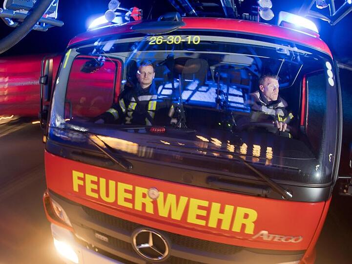 Feuerwehrleute sitzen für Fotoaufnahmen in einem Leiterwagen (Aufnahme mit langer Verschlusszeit). Foto: Julian Stratenschulte/Archiv