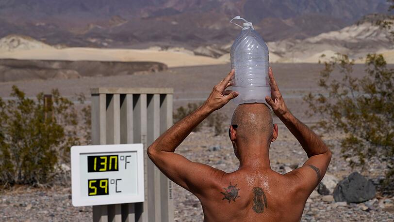 Ein Mann kühlt sich im "Death Valley"-Nationalpark mit einer mit Eiswasser gefüllten Plastikflasche auf dem Kopf ab.