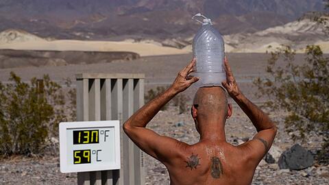 Ein Mann kühlt sich im "Death Valley"-Nationalpark mit einer mit Eiswasser gefüllten Plastikflasche auf dem Kopf ab.