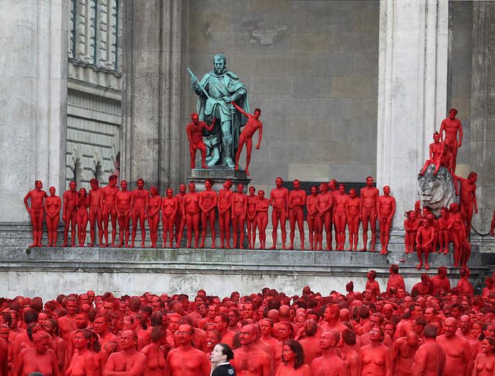 Star-Fotograf Spencer Tunick lässt zur Eröffnung der Opernfestspiele für seine Installation hunderte bunt angemalte Menschen durch München laufen. Das Highlight: Die rot-goldenen Teilnehmer stellen sich an Münchner Monumenten entlang der Ludwigstraße auf. Hier gibts die Bilder!