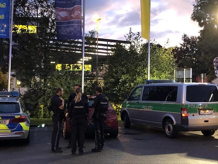 Fahrzeuge von Polizei und Feuerwehr stehen auf dem Parkplatz des Supermarktes in Abensberg. Ein 39 Jahre alter Mann ist aus ungeklärter Ursache erschossen worden.
