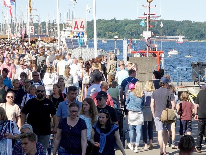 Tausende von Menschen gehen am ersten Tag der Kieler Woche über die Kiellinie.