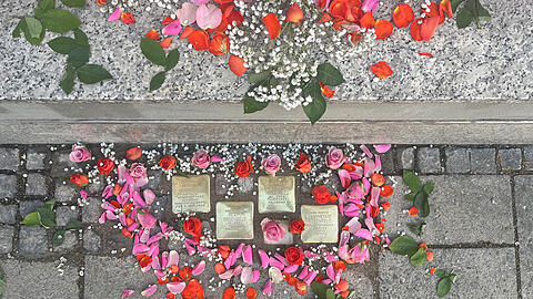 Zur Gedenkfeier mit Rosenbl&auml;ttern geschm&uuml;ckt: die vier neuen M&uuml;nchner Stolpersteine f&uuml;r die Familie Rosenfeld an der Buttermelcherstra&szlig;e 4.