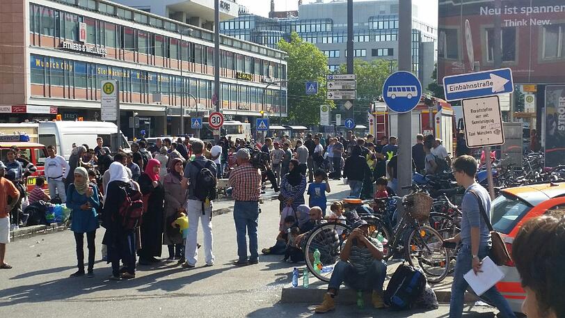Völlig erschöpft rasten die Flüchtlinge auf dem Bahnhofsvorplatz an der Arnulfstraße und warten auf ihre Registrierung.
