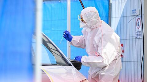 Ein Mitarbeiter führt in einem Corona-Abstrichzentrum einen Test durch.