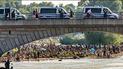 Dichtgedrängt sitzen die Menschen an der Reichenbachbrücke in der Sonne, während von oben die Polizei nur zuschauen kann.