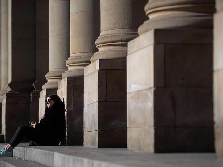 Eine junge Frau genießt die Sonne vor dem Königsbau in der Stuttgarter Innenstadt.