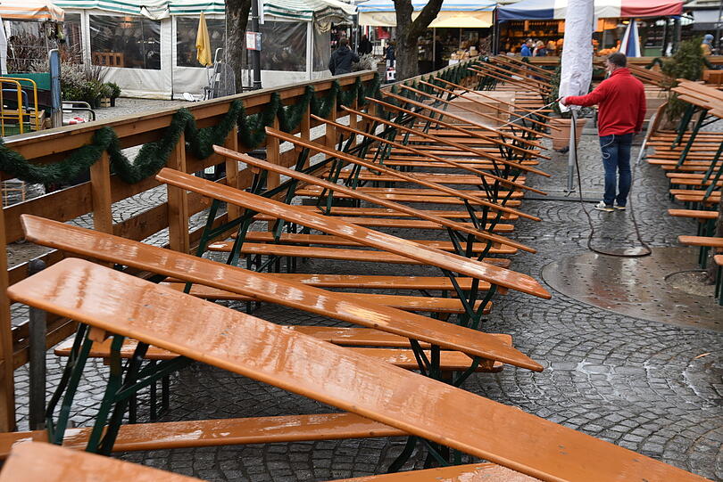 Der hartnäckige Sahara-Sand hat sich auch am Viktualienmarkt abgesetzt. Ein Mitarbeiter des Biergartens befreit am Mittwoch die Bierbänke und -tische von der Sandschicht.