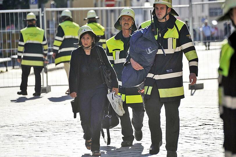 Eine Anwohnerin darf kurz in ihre Wohnung &ndash; mit Helm und in Begleitung der Feuerwehr.