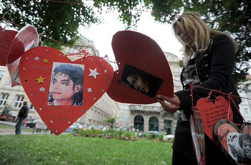 Ein weiblicher Fan steht am Samstag vor dem inoffiziellen Michael-Jackson-Denkmal vor dem Hotel in München, in dem der US-amerikanische Sänger bei seinen Münchenbesuchen abzusteigen pflegte, und schaut sich eine Kette aus Herzen mit Jacko-Portraits an.