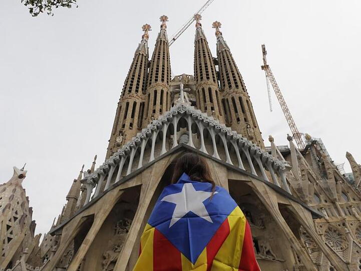 Eine Demonstrantin steht vor Barcelonas Wahrzeichen, der Sagrada Familia.