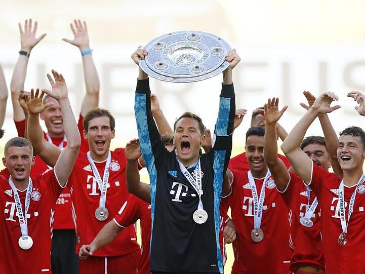 Münchens Torwart Manuel Neuer (M.) hält die Meisterschale und jubelt über den Sieg. Foto: Kai Pfaffenbach/Reuters-Pool/dpa