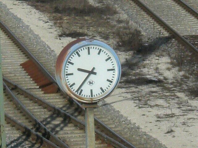 Detailaufnahme einer etwas angerosteten, typischen Bahnhofsuhr.