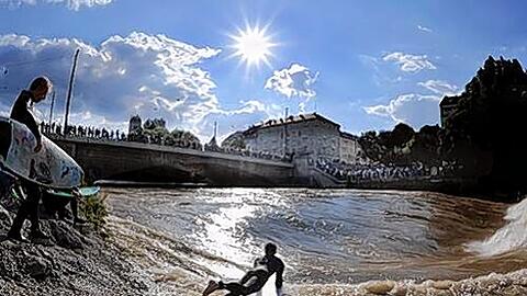 Ein so genannter Flußsurfer stürzt sich mit seinem Surfbrett in die durch Hochwasser angestiegene Isar.