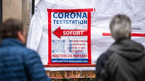 Menschen warten in der Stuttgarter Innenstadt vor einem Corona-Testzentrum auf ihren Abstrich.