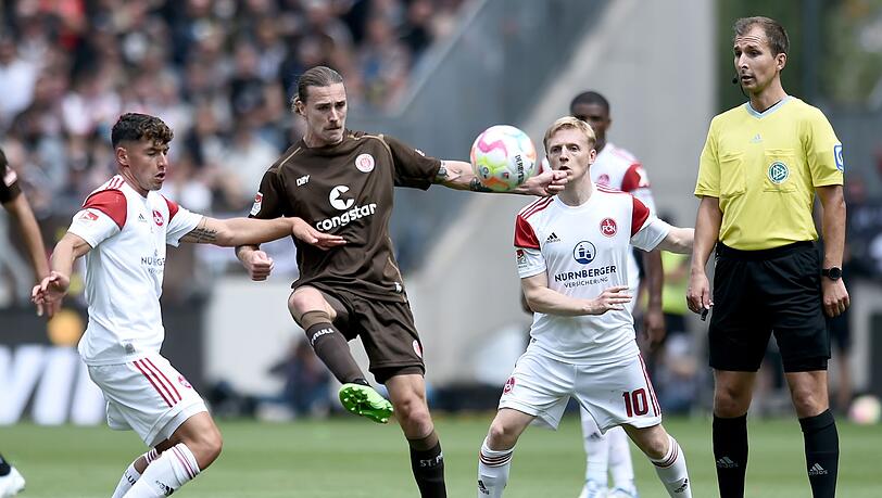 St. Paulis Jackson Irvine (M) gegen Nürnbergs Taylan Duman (l) und Mats Möller Daehli, rechts steht Schiedsrichter Florian Heft.