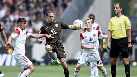 St. Paulis Jackson Irvine (M) gegen Nürnbergs Taylan Duman (l) und Mats Möller Daehli, rechts steht Schiedsrichter Florian Heft.