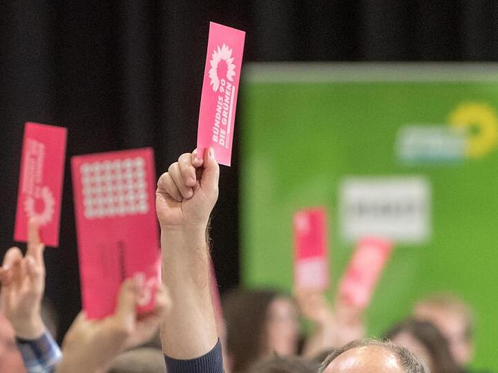 Delegierte halten beim Landesparteitag der bayerischen Grünen ihre Wahlzettel nach oben. Foto: Armin Weigel/Archiv
