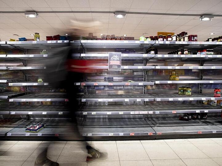 Eine Person geht in einem Supermarkt an einem fast leeren Regal vorbei. Foto: Christoph Soeder/dpa/Archivbild