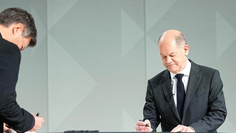 Der Grünen-Vorsitzende Robert Habeck (l) und der neue Kanzler Olaf Scholz (SPD) setzen ihre Unterschriften unter das Dokument.