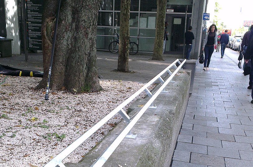 Vor dem Amt für Wohnen und Migration in der Franziskanerstraße sperrt ein Geländer das Mäuerchen zum Sitzen.