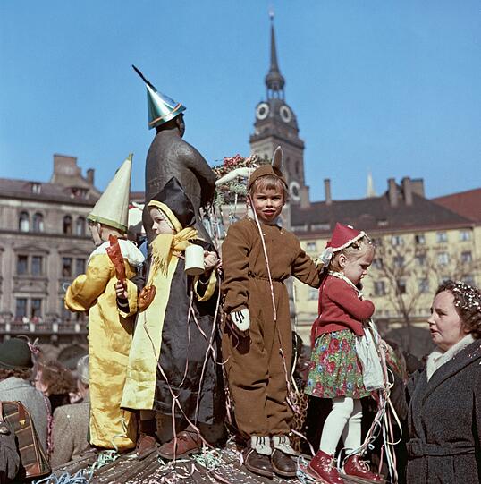 1955 beim Fasching am Weiß-Ferdl-Brunnen, auf dem die Zwergerl hier postiert worden sind. Die Verkleidung als Haserl, Münchner Kindl und Rotkäppchen scheinen gerade im Trend zu liegen.