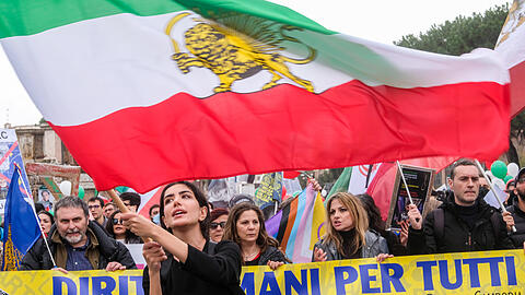 Eine Frau schwenkt während einer Demonstration eine iranische Fahne.