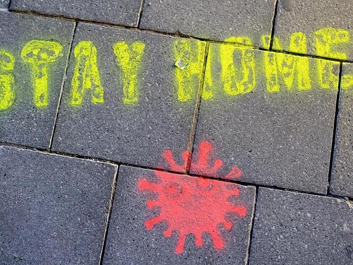 Ein Graffiti bestehend aus dem Text "Stay Home" und einer symbolischen Virusdarstellung. Foto: Sven Hoppe/dpa