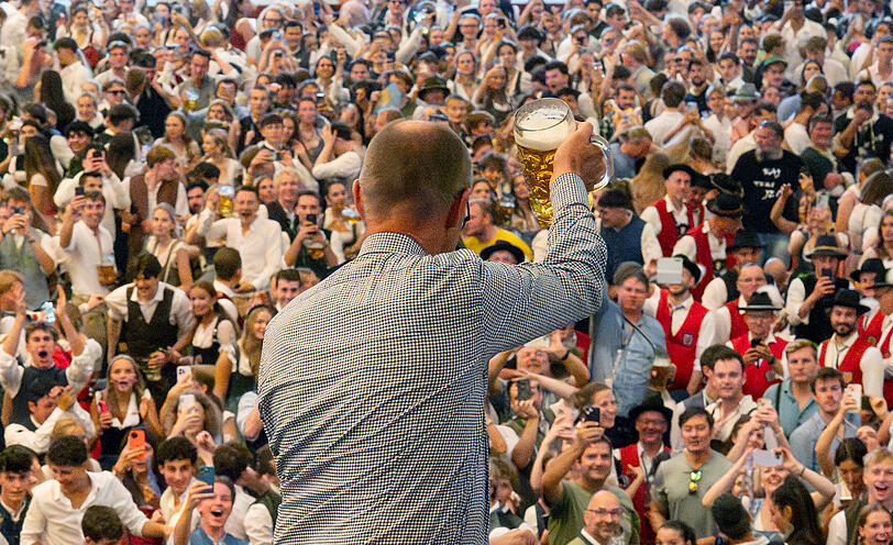 Bundeskanzler Friedrich Merz prostet den Besuchern im Schottenhamel zu.