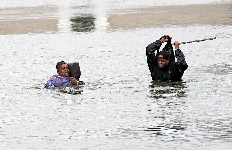 Ein Mann und eine Frau waten in Houston durch das die Straßen überflutende Wasser.