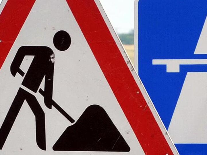 Ein Baustellenschild ist vor einem Autobahschild platziert. Foto: Martin Schutt/Archiv