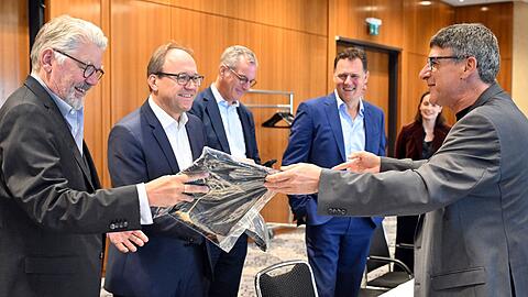 Zum Beginn der Tarifverhandlungen in der Stahlindustrie überreicht der Verhandlungsführer der IG Metall, Knut Giesler, zwei T-Shirts an den Verhandlungsführer der Arbeitgeber, Reiner Blaschek (2.v.l), sowie den Geschäftsführer des Arbeitgeberverbandes Stahl, Gerhard Erdmann (l).