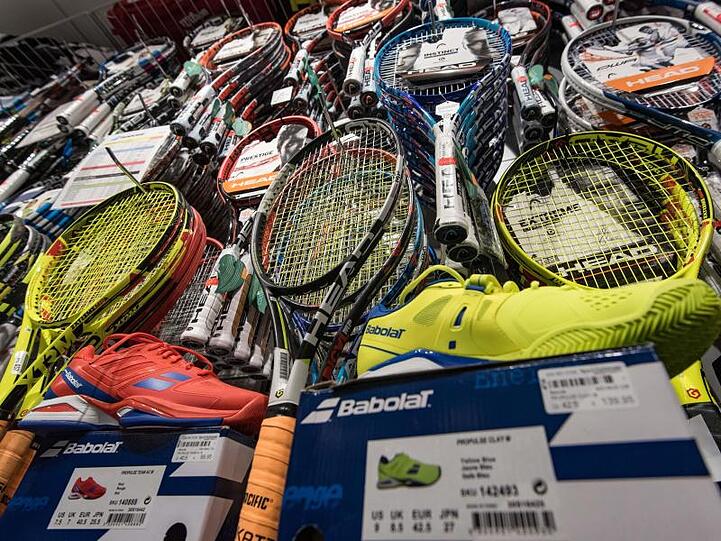 Tennisschläger und Tennisschuhe stehen in einem Regal in einem Geschäft. Foto: Daniel Maurer/dpa/Archivbild