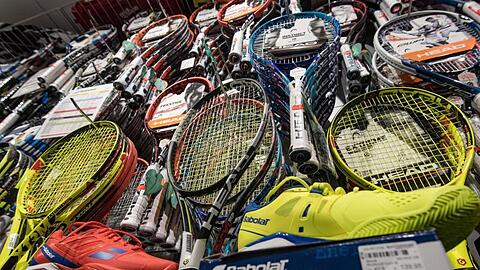 Tennisschläger und Tennisschuhe stehen in einem Regal in einem Geschäft. Foto: Daniel Maurer/dpa/Archivbild