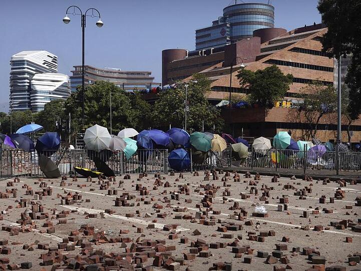 Auf einer Straße vor einer Barrikade, die von Demonstranten der Polytechnischen Universität Hongkong gebaut wurde, sind Ziegelsteine verstreut.