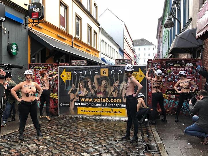 Mit nacktem Oberkörper und einer Flex demontieren Aktivistinnen im Rotlichtviertel von St. Pauli einen Sichtschutz der Herbertstraße.