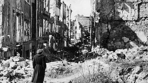 Im Trümmerland: Eine Frau geht in einer Straße in Dresden an Häusern vorbei, von denen nach Bombenangriffen im Zweiten Weltkrieg nur noch Ruinen geblieben sind.