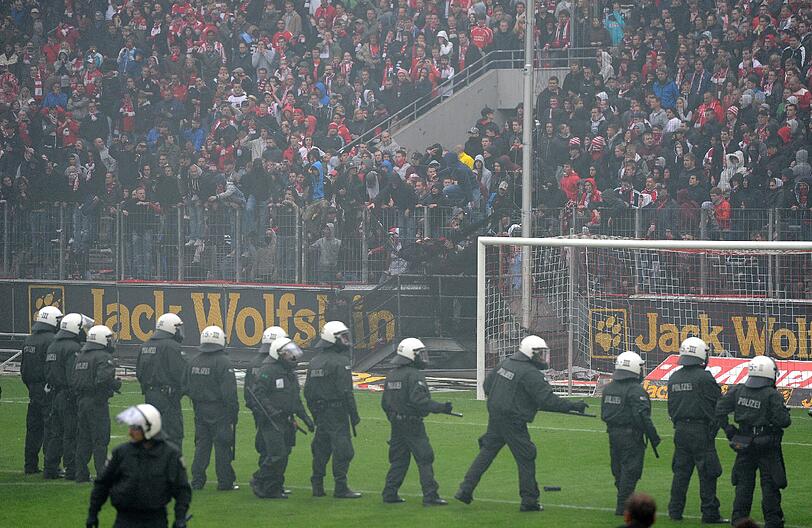 05.05.2012 Mit dem Schlusspfiff stürmen Hooligans des 1. FC Köln nach der 1:4-Niederlage gegen Bayern München den Platz und können nur von einem massiven Polizeiaufgebot in Schach gehalten werden. Zuvor waren bereits auf der Kölner Fantribüne Rauchbomben und Bengalische Feuer gezündet worden.