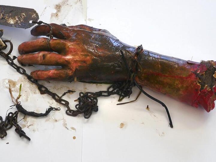 Ein abgetrennter Arm aus Gummi als Scherzartikel liegt auf einem Tisch. Foto: -/Polizeipräsidium Schwaben Nord/dpa