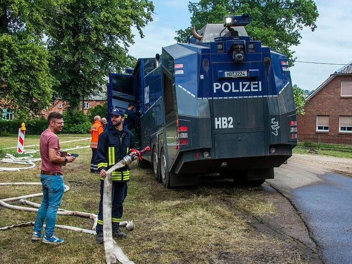 Alles, was löschen kann, ist im Einsatz: Ein Wasserwerfer der Polizei wird im evakuierten Ort Alt Jabel mit Löschwasser aufgetankt.