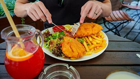 Ein Mann isst ein Schnitzel im Restaurant. Die Mehrwertsteuer auf Essen will die Groko wieder auf sieben Prozent reduzieren.