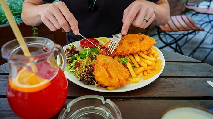 Ein Mann isst ein Schnitzel im Restaurant. Die Mehrwertsteuer auf Essen will die Groko wieder auf sieben Prozent reduzieren.